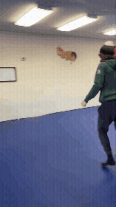 Person In Green Jacket Standing On Blue Mat GIF