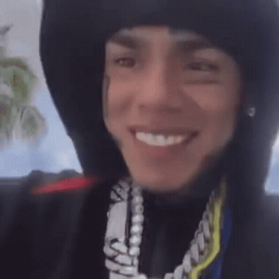 Person In Hoodie And Necklace Smiling GIF