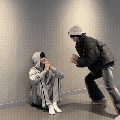 Person In Hoodie With Chinese Symbol Squatting Next To Another GIF