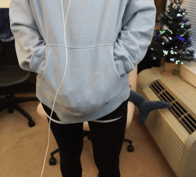 Person In Light Blue Hoodie And Black Pants In Front Of Christmas Tree GIF
