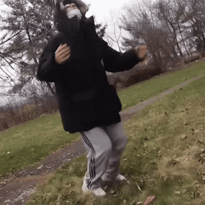 Person In Mask And Black Jacket Dancing In Grass GIF