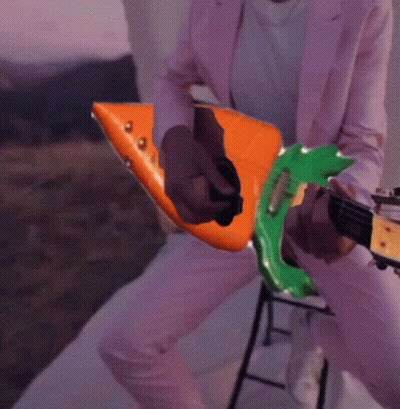 Person In Pink Suit Playing Orange And Green Guitar GIF