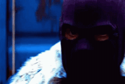 Person In Purple Mask Standing In Dark Room GIF