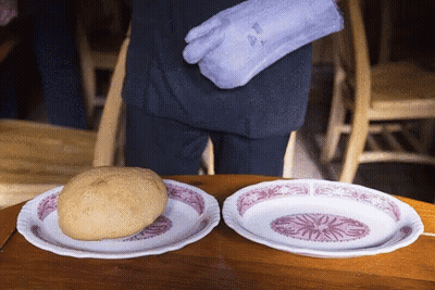 Person In Purple Oven Mitt Holding Bread Between Two Plates GIF