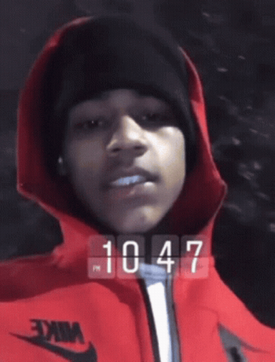 Person In Red Jacket And Black Beanie At 10:47 GIF