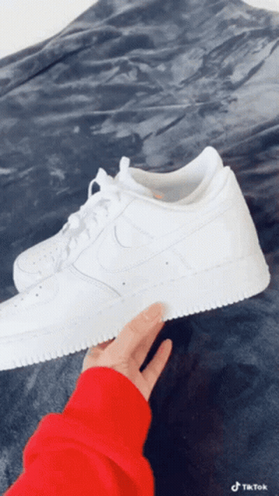 Person In Red Sweater Holding White Nike Sneakers GIF