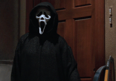 Person In Scream Mask Standing By Wooden Door GIF