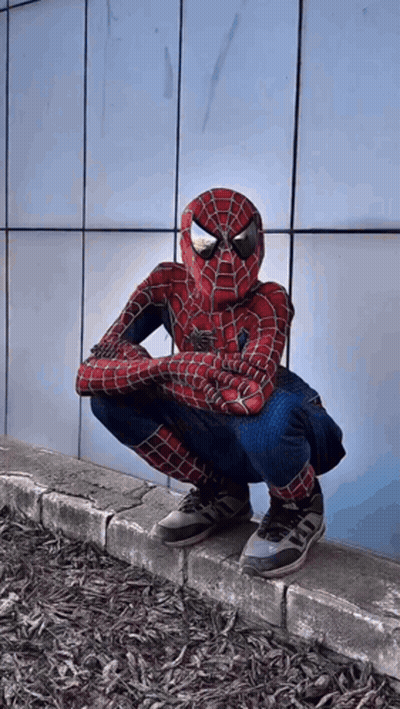 Person In Spiderman Costume Squatting On Sidewalk GIF