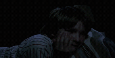 Person In Striped Shirt Laying On Bed In Dark GIF