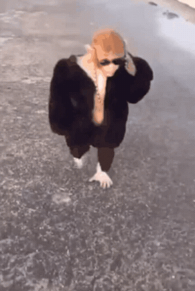 Person In Sunglasses And Fur Coat Walking Barefoot In Water GIF