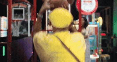 Person In Yellow Hat In Front Of Arcade Sign GIF