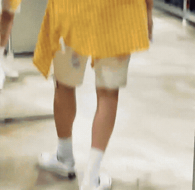 Person In Yellow Shirt And White Shorts Walking Down Hallway GIF