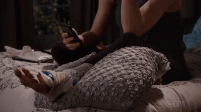 Person Laying On Bed With Bandaged Foot And Cell Phone GIF