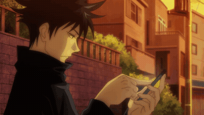 Person Looking at Cell Phone in Front of Brick Wall