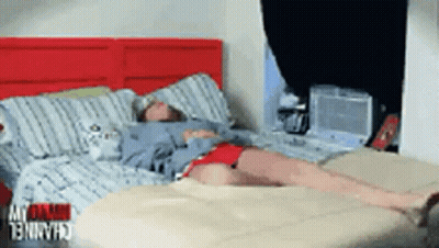 Person Lying On Bed With Red Headboard GIF