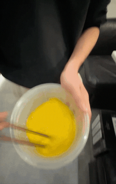Person Mixing Yellow Liquid With Chopsticks In Bowl GIF