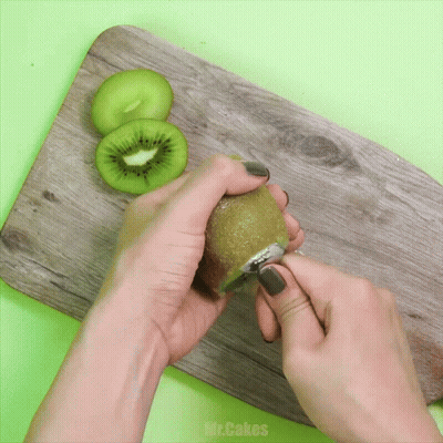 Person Peeling Kiwi On Wooden Board With Mr.Cakes GIF