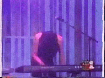 Person Playing Keyboard At Microphone With Purple Light GIF