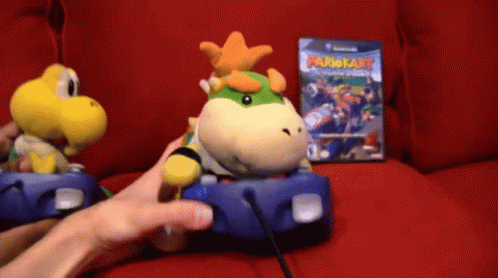 Person Playing Video Game With Stuffed Mario Kart Character GIF