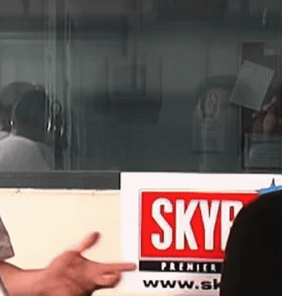 Person Pointing at Skyp Sign in Front of Window