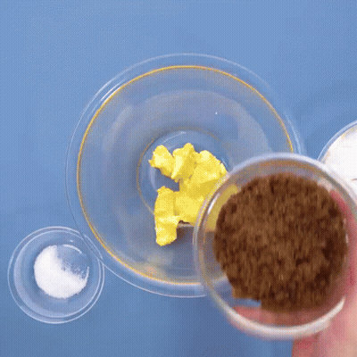 Person Pouring Brown Sugar Into Glass Bowl GIF