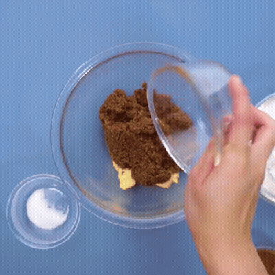 Person Pouring Brown Sugar Into Glass Bowl GIF