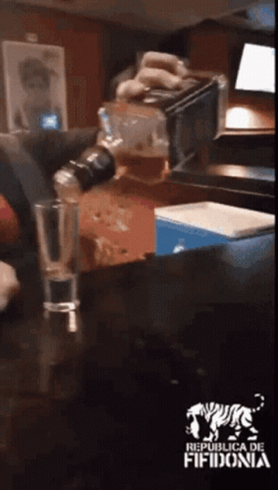 Person Pouring Drink Into Glass With Republica De Fifidonia Logo GIF