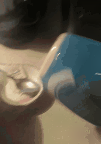 Person Pouring Into Glass With Blue Container GIF