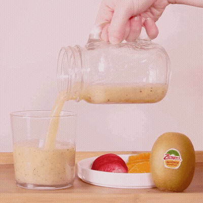 Person Pouring Smoothie Into Glass With Kiwi GIF