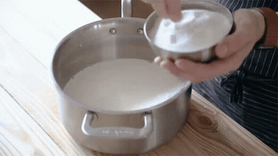 Person Pouring Sugar Into Pot Of Milk GIF