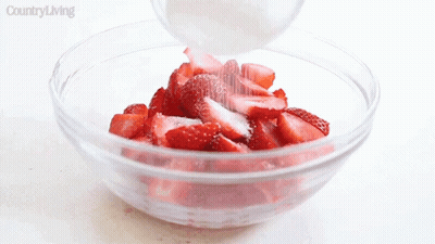 Person Pouring Sugar Into Strawberries In Glass Bowl GIF
