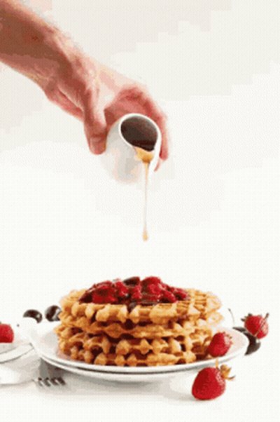 Person Pouring Syrup On Waffles With Strawberries GIF