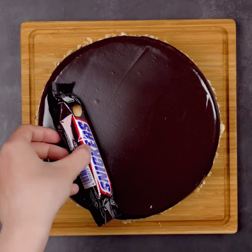 Person Putting Snickers Bar Into Chocolate Cake GIF