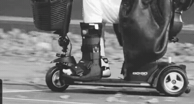 Person Riding Mobility Scooter In Black And White GIF
