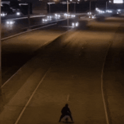 Person Riding Skateboard Down Street At Night GIF