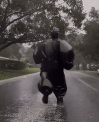 Person Running Down Wet Street With Umbrella In Rain GIF