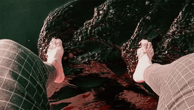 Person's Feet Standing On Rock In Water GIF