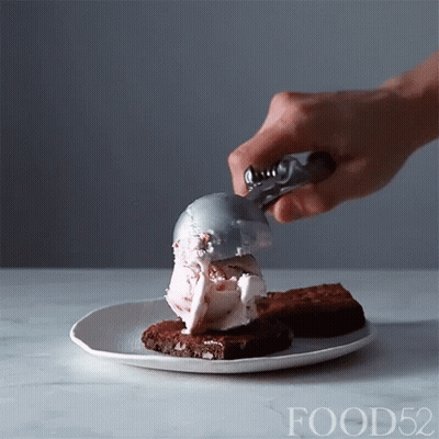 Person Scooping Ice Cream Onto Brownies GIF