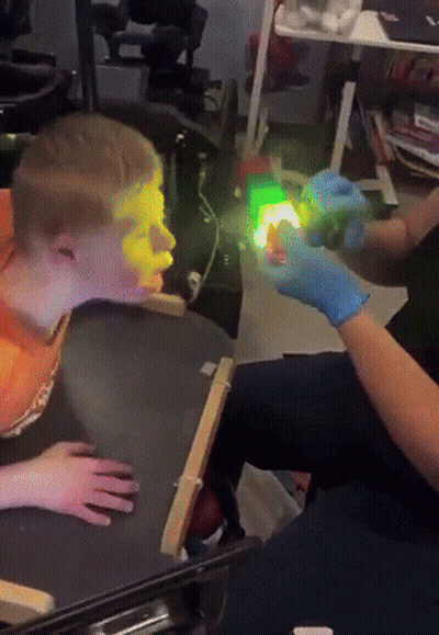 Person Shining Green Light On Boy's Face GIF
