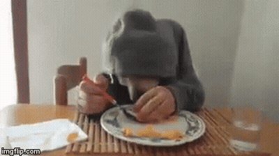Person Sitting At Table Eating With Fork And Spoon GIF