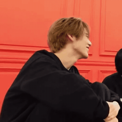 Person Sitting In Front Of Red Wall GIF