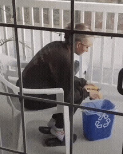 Person Sitting Next To Blue Recycle Trash Can GIF