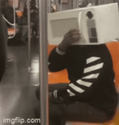 Person Sitting On Bus With Microwave In Front Of Head GIF