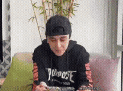 Person Sitting On Couch In Black 'Purpose' Hoodie GIF
