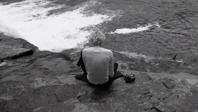 Person Sitting On Rock Near River GIF