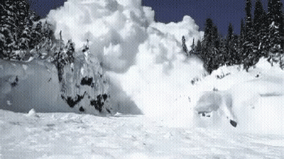 Person Skiing Down Snow-Covered Mountain Slope GIF