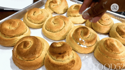 Person Sprinkling Powdered Sugar On Rolls With Number 52 GIF