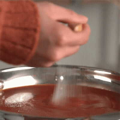 Person Sprinkling Salt Into Pot Of Sauce GIF