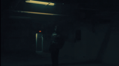 Person Standing In Dark Room With Red Exit Sign GIF