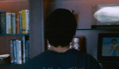 Person Standing In Front Of Bookshelf With Apollo 11 Book GIF